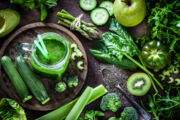 Top view of a rustic table filled with green fruits and vegetables for a perfect detox diet. At the left of an horizontal frame is a glass with fresh green smoothie and a large variety of fruits and vegetables are all around it. Predominant color is green. Low key DSRL studio photo taken with Canon EOS 5D Mk II and Canon EF 100mm f/2.8L Macro IS USM