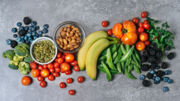 Fresh vegetables, fruits, and nuts on gray background